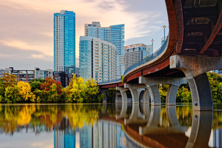 Panoramic view of Austin, Texas skyline featuring prominent skyscrapers like The Independent, The Austonian, and the Frost Bank Tower.