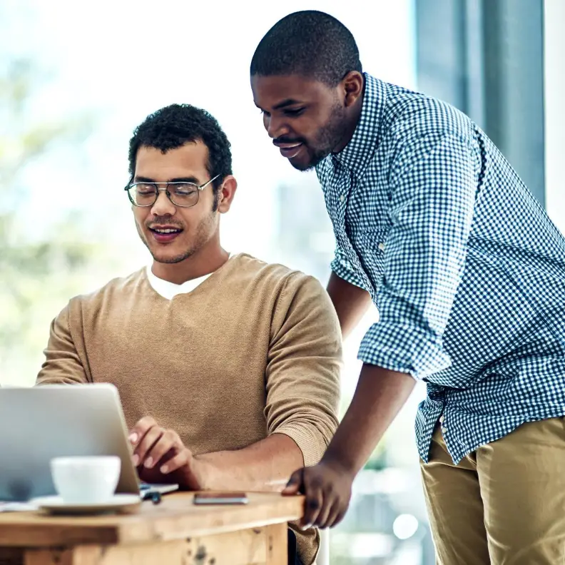 Team collaborating over a laptop in a bright office – managed IT services planning session